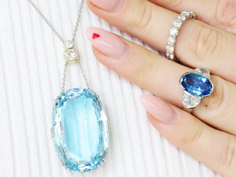 A large oval facet-cut light blue aquamarine pendant suspended from two diamonds set in platinum on a fine chain. View III