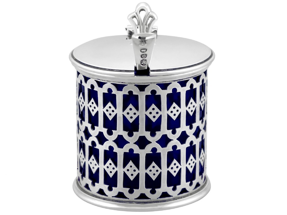 A pierced sterling silver mustard pot featuring geometric openwork, a cobalt blue glass liner, a flat hinged lid, and an accompanying spoon. View V