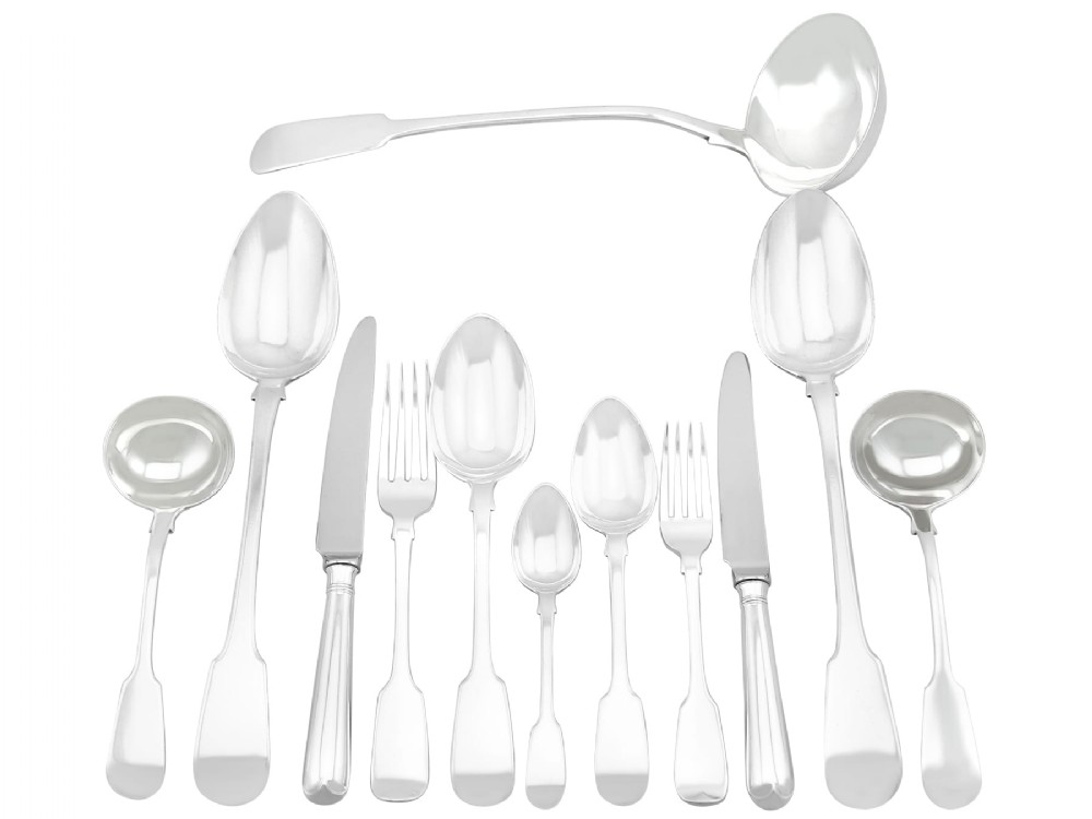An antique Victorian sterling silver cutlery set in the Fiddle pattern, featuring knives, forks, spoons, and ladles arranged on a plain white background.