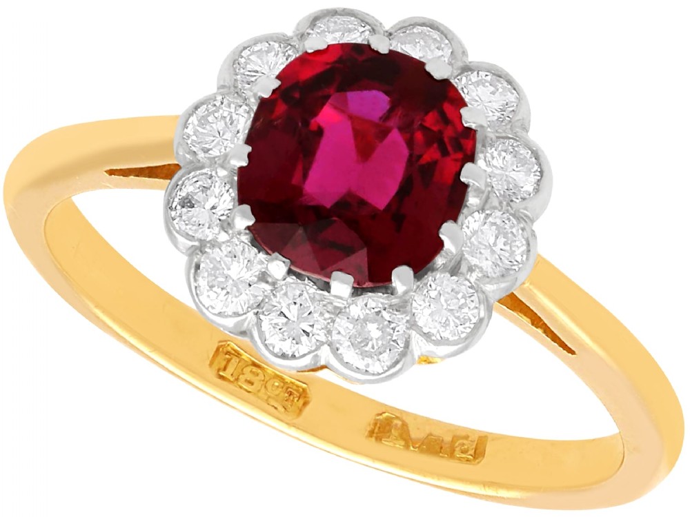 An 18ct yellow gold cluster ring featuring a central cushion cut red ruby framed by a halo of round diamonds.