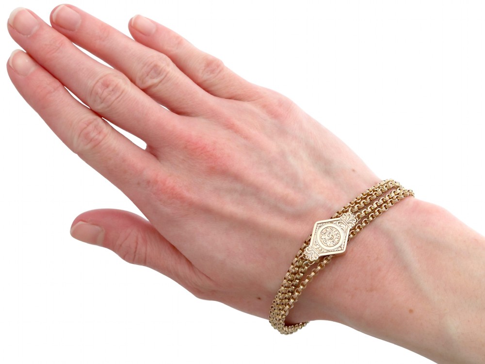 A late Victorian four-strand 9ct yellow gold belcher chain bracelet featuring a central hand-engraved lozenge-shaped panel. View X
