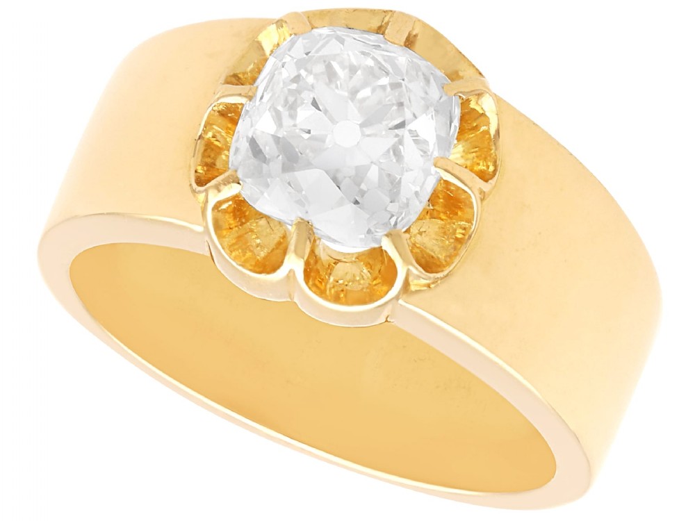 An antique 18ct yellow gold solitaire ring featuring a broad band and a cushion cut diamond set in a scalloped collet.