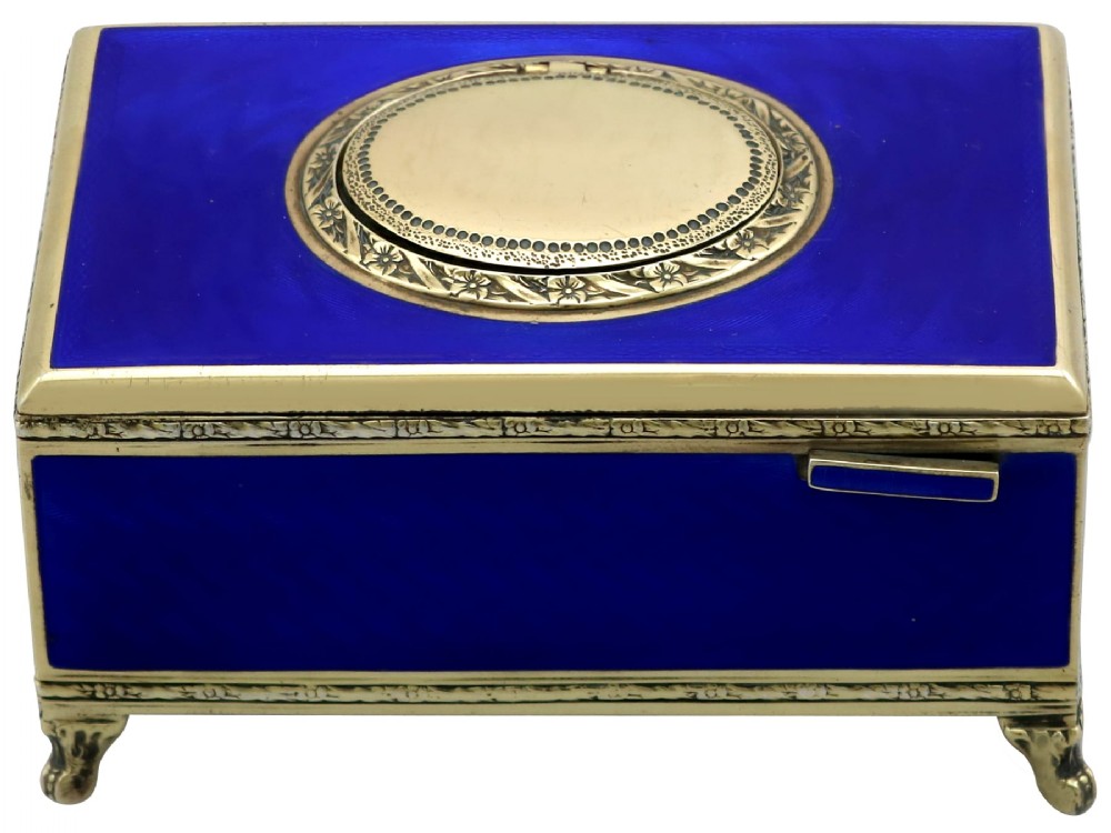 A rectangular cobalt blue guilloche enamel and silver-gilt singing bird box with an engraved oval hatch cover and tiny cabriole feet.