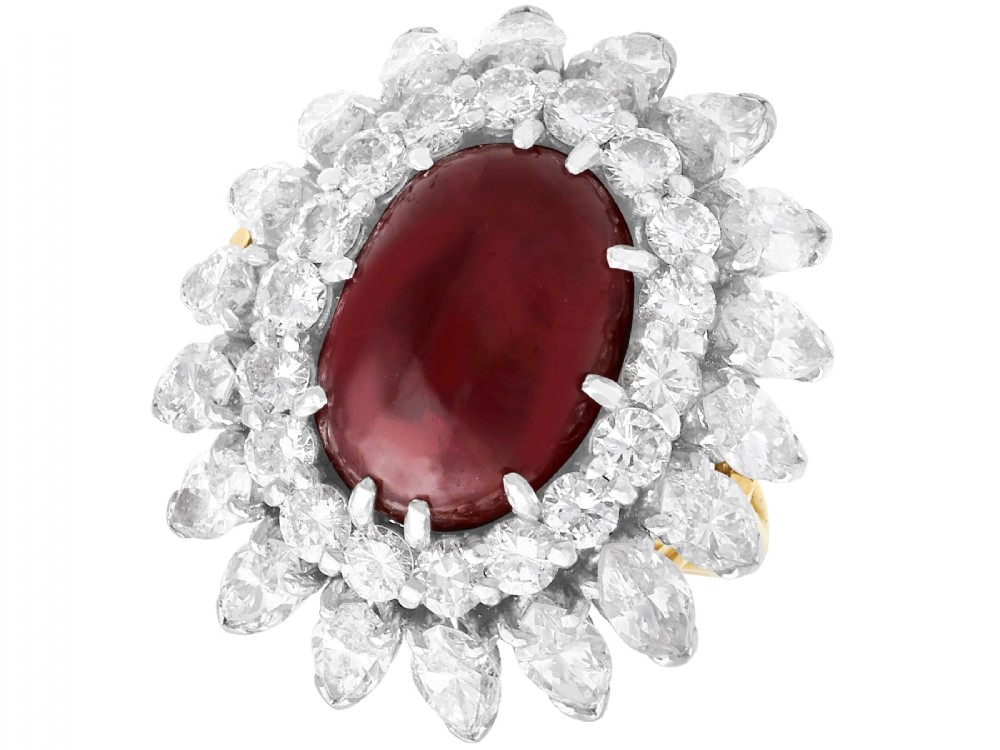 A vintage 18ct yellow gold ring featuring a central oval cabochon red ruby surrounded by a double tiered cluster halo of diamonds.