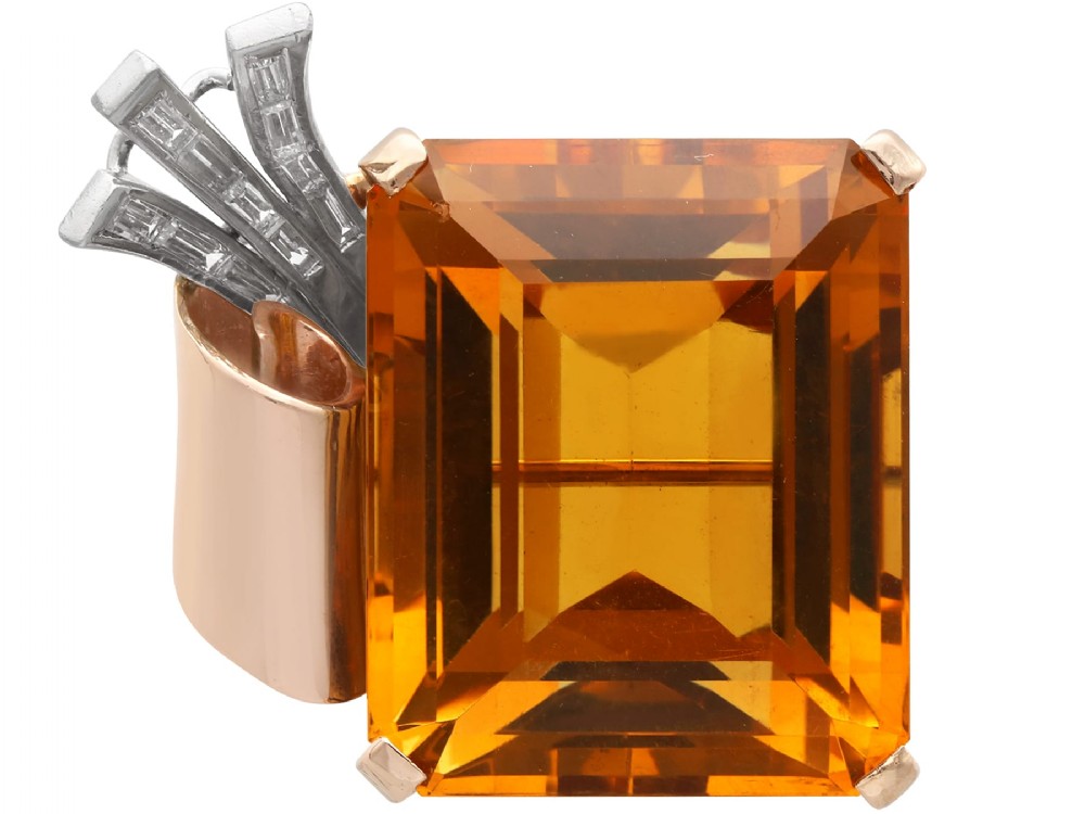 A large emerald-cut amber citrine stone set in a 14ct yellow gold brooch mounting accented with baguette diamonds.