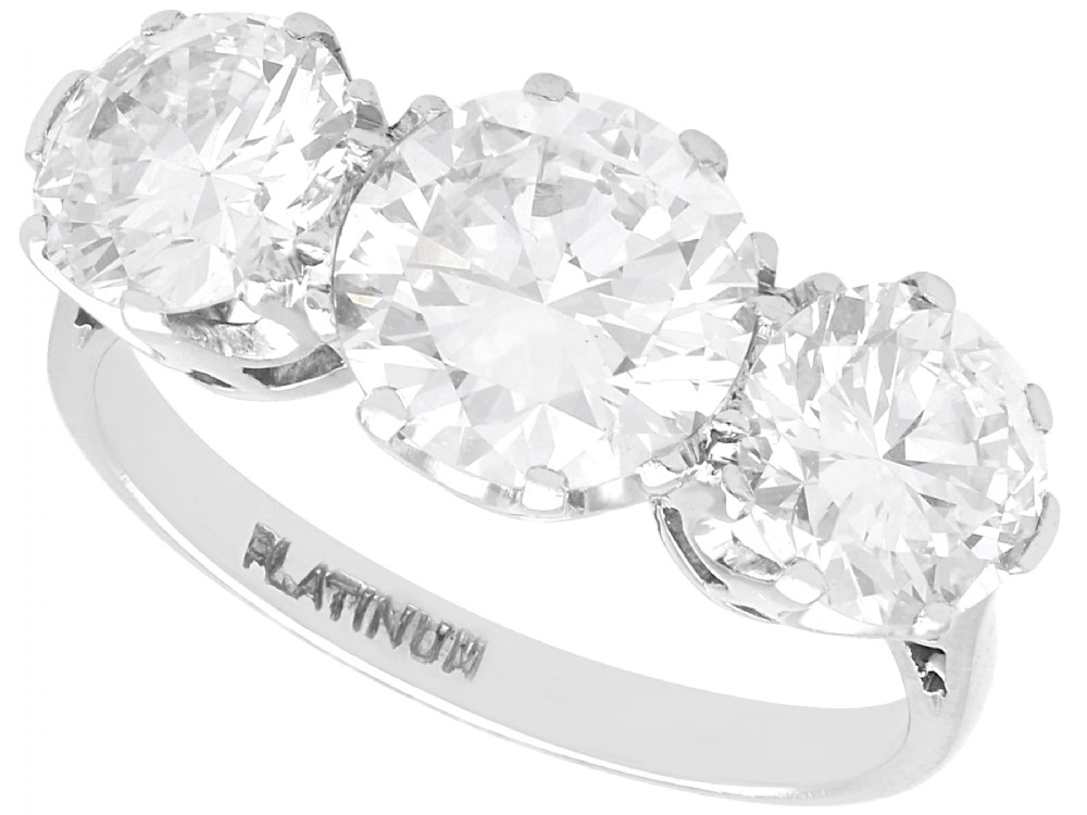 A vintage platinum ring featuring three large round brilliant cut diamonds set horizontally in claw settings.