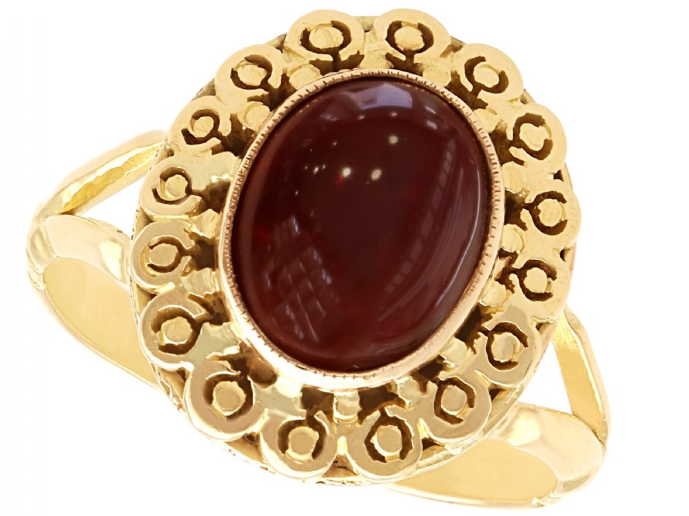 A vintage 18ct yellow gold dress ring set with a central oval cabochon garnet encircled by an openwork gold pattern border.