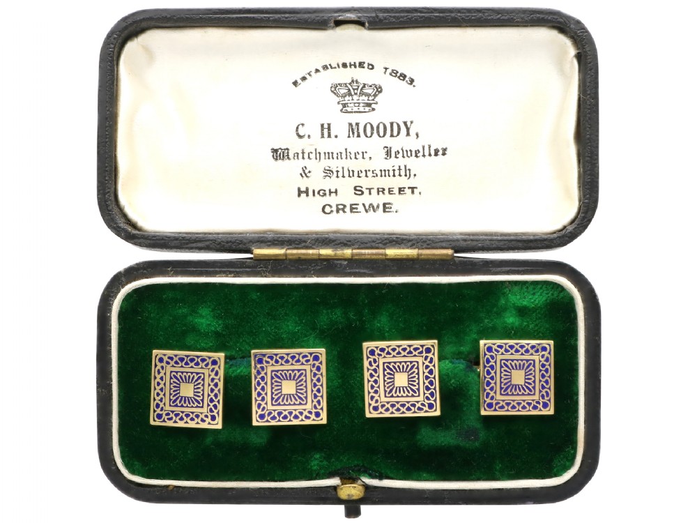 A set of four square 18ct yellow gold cufflinks decorated with blue enamel geometric patterns, presented inside a fitted black box.