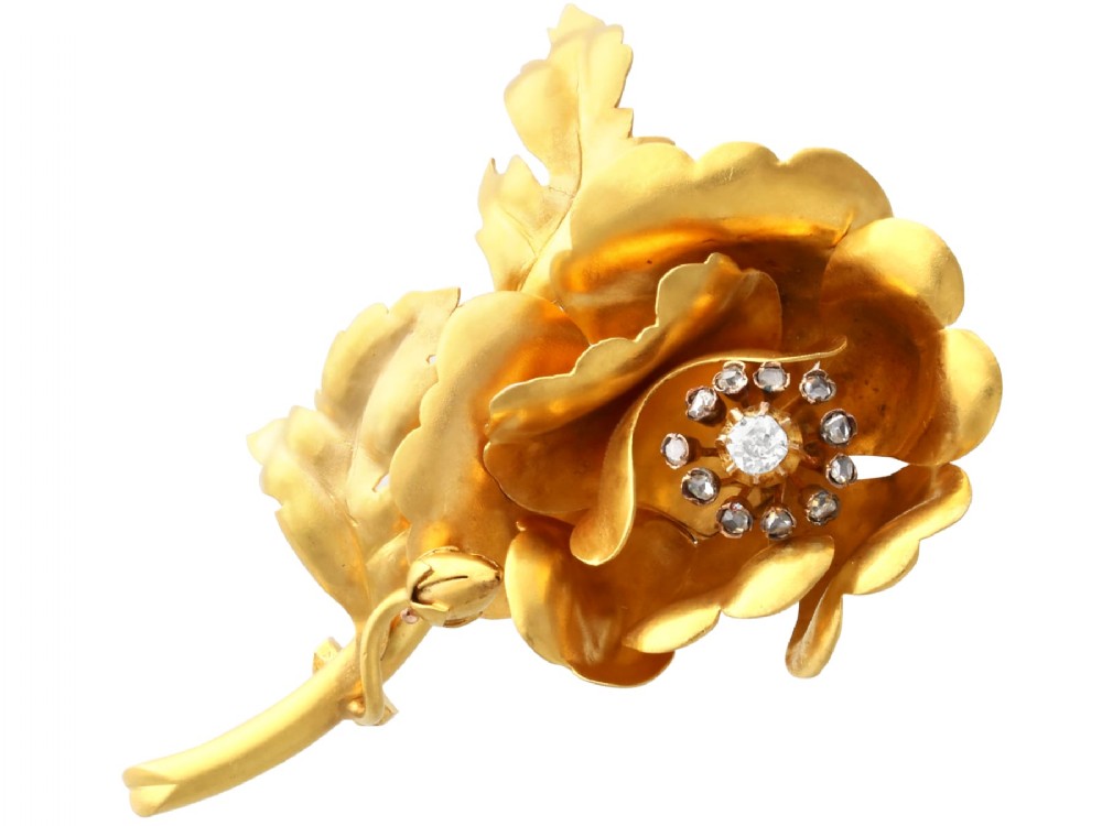 An antique Victorian 22ct yellow gold floral brooch featuring sculpted petals, leaf details, and a central cluster of diamonds.