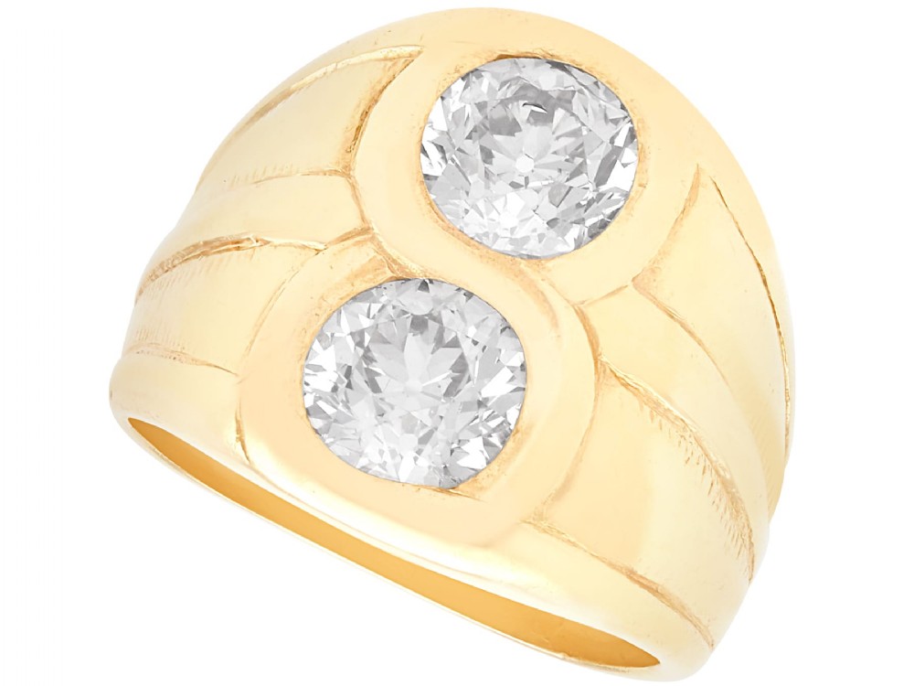 A wide 14ct yellow gold ring featuring two round diamonds set vertically within carved linear accents.