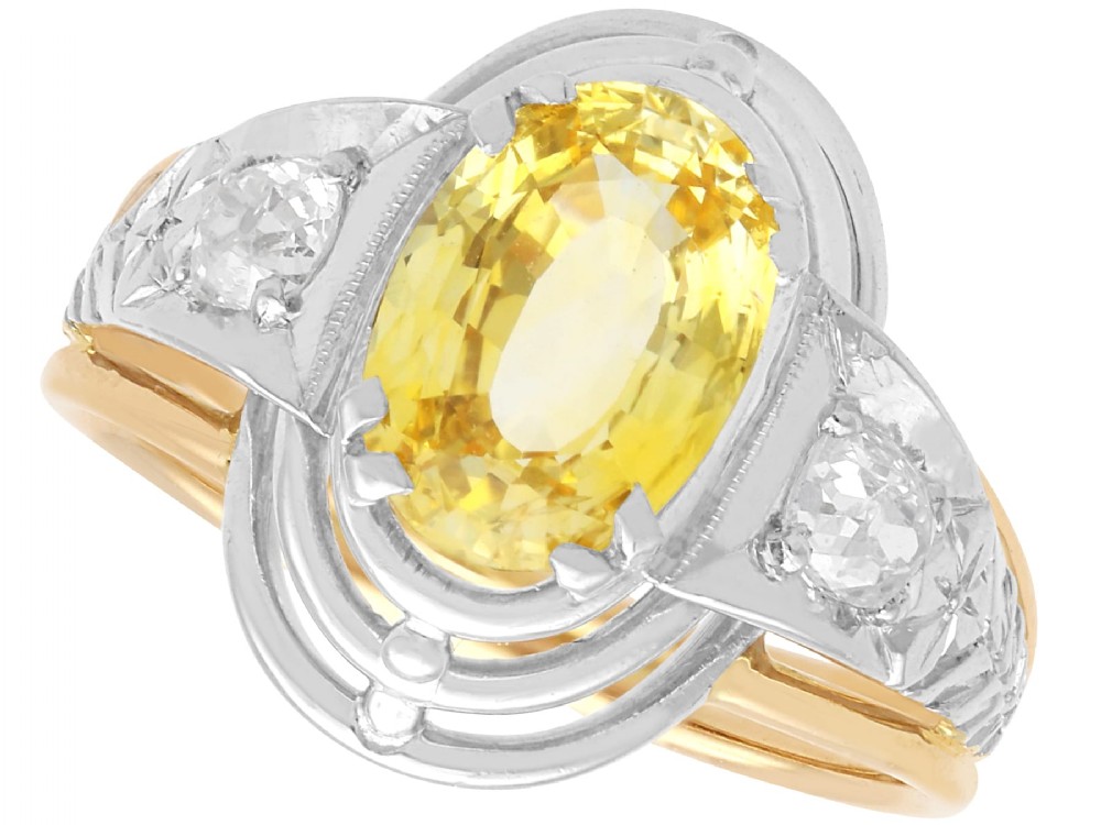 An Art Deco 18ct yellow gold and platinum ring featuring a central oval yellow sapphire flanked by single diamonds.