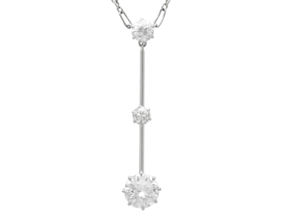 An 18ct white gold Art Deco pendant featuring three linear claw-set round diamonds suspended on a delicate chain.