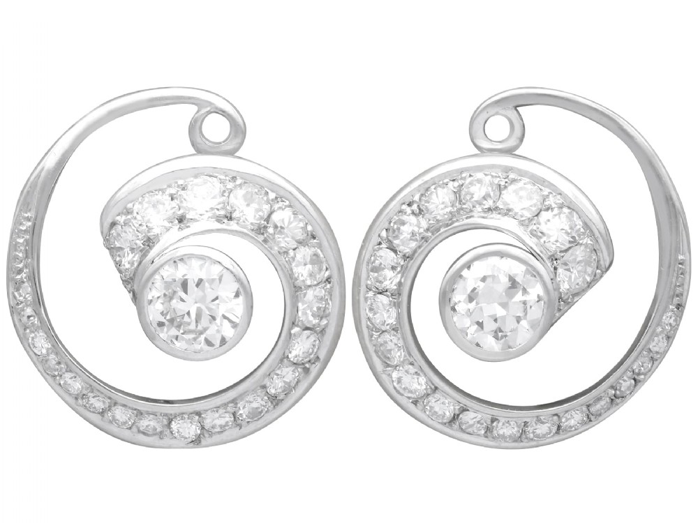 A pair of 14ct white gold twirl earrings featuring round brilliant cut diamonds set in a concentric spiral design around a central diamond.