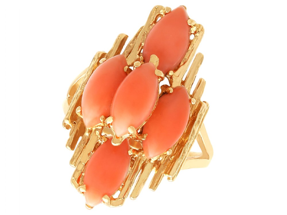 A 1960s 14ct yellow gold cocktail ring featuring five marquise cabochon corals set within a textured abstract gold framework.