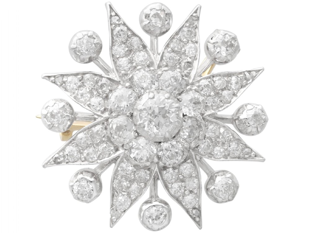 An antique Edwardian silver-topped diamond star brooch featuring a central round diamond surrounded by diamond-paved star rays and ball terminals.