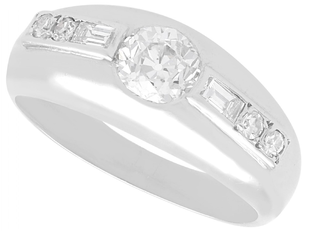 A vintage platinum ring featuring a centre round brilliant diamond flanked by baguette and round cut diamonds set into a broad band.