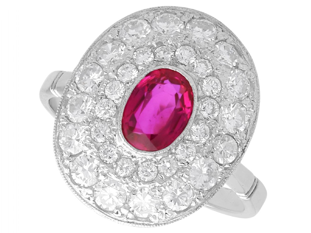An 18ct white gold halo ring featuring a central oval red ruby surrounded by two tiers of round diamonds.