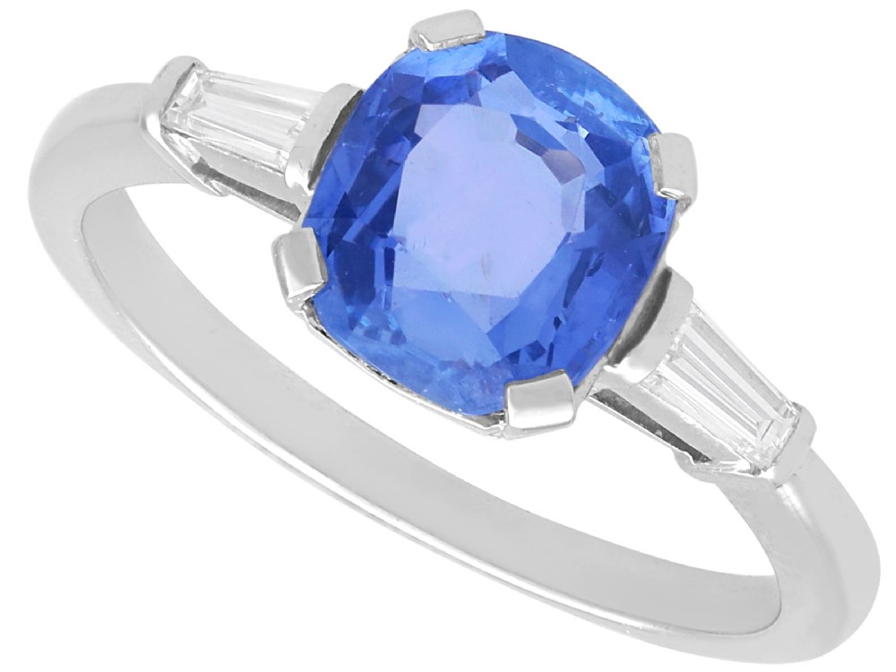 An Art Deco platinum ring featuring a cushion-cut blue sapphire flanked by two tapered baguette diamonds.