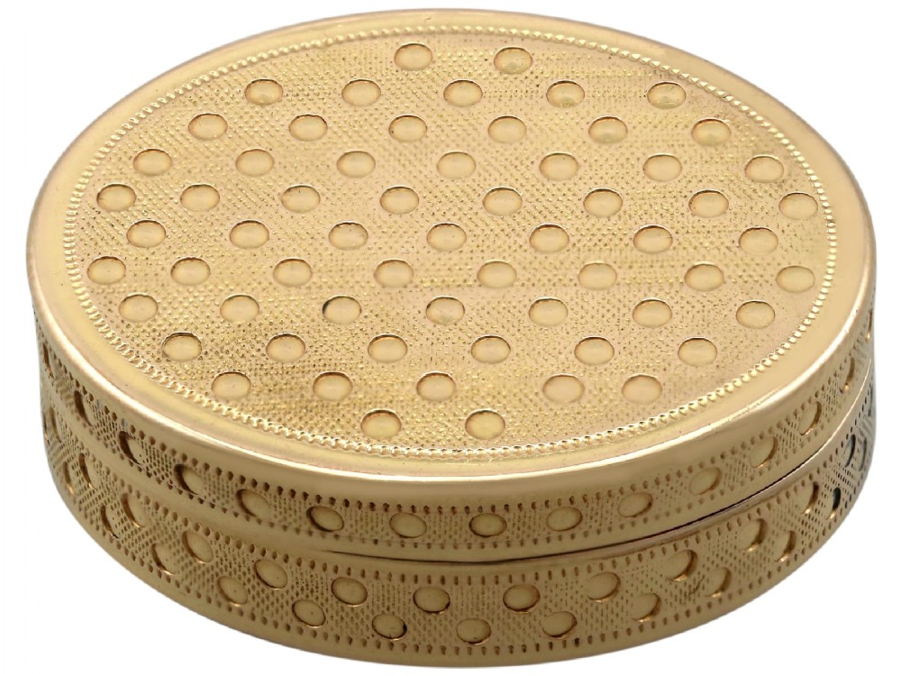 An oval antique 18ct yellow gold vinaigrette featuring an engine-turned pattern with polished circular dot accents.