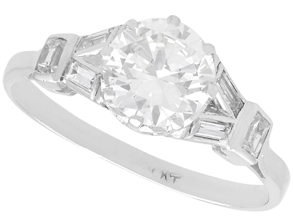 An Art Deco platinum ring featuring a central round solitaire diamond flanked by geometric baguette-cut diamond shoulders.