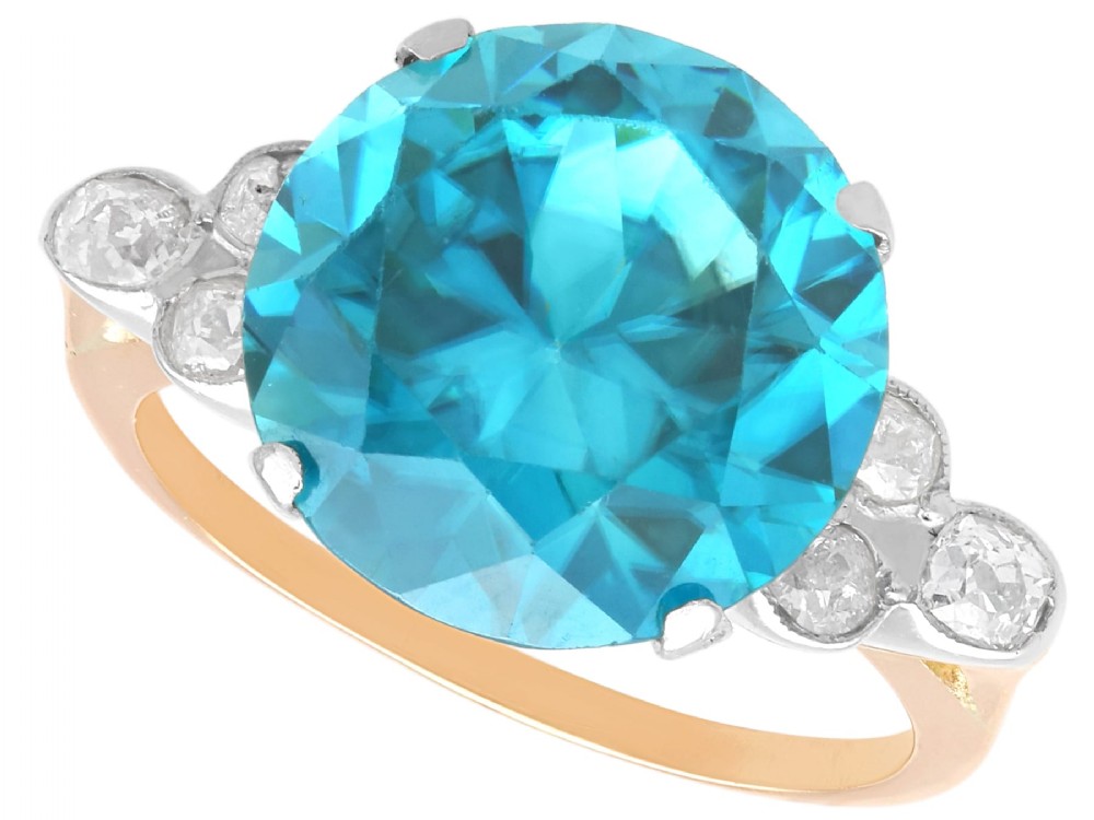 An Art Deco 9ct yellow gold ring featuring a large round-cut blue zircon flanked by diamond-set shoulders.