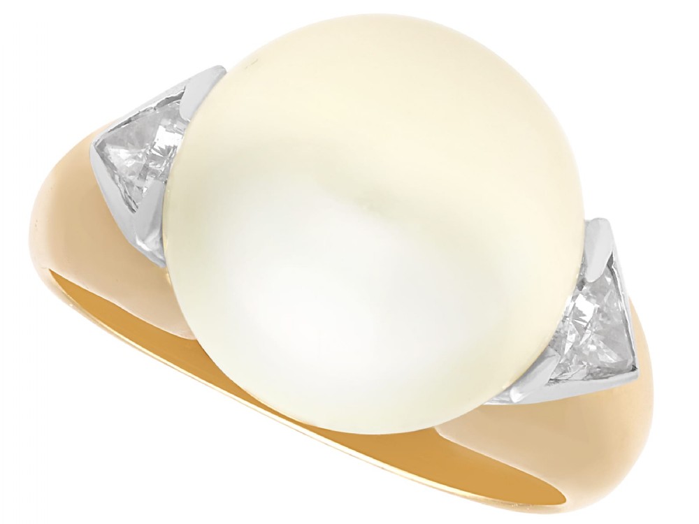A vintage 18ct yellow gold ring featuring a central round cream cultured pearl flanked by two triangular diamonds.