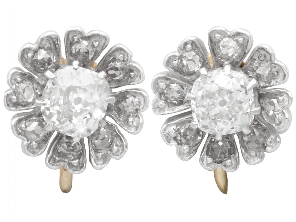 Pair of late nineteenth-century floral cluster earrings featuring central cushion-cut diamonds surrounded by silver-set diamond petals with yellow gold fittings.