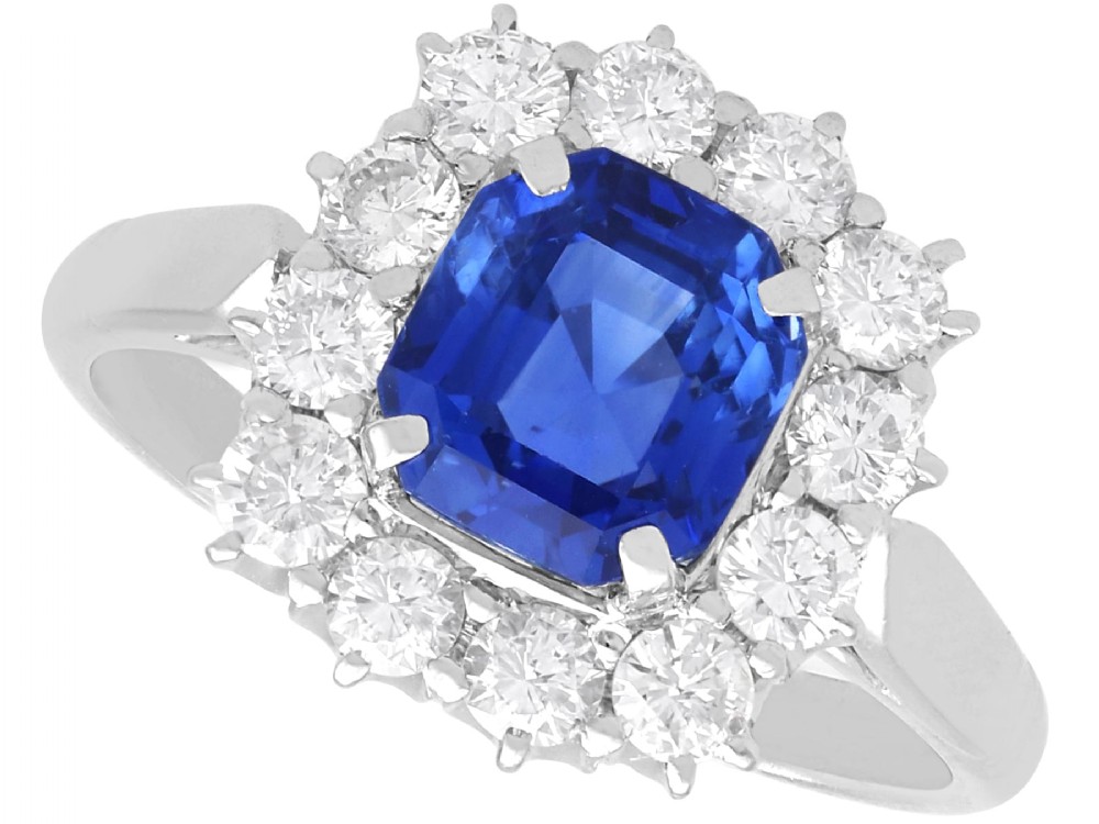 A vintage platinum dress ring featuring a cushion-cut blue Ceylon sapphire surrounded by a cluster of round brilliant-cut diamonds.