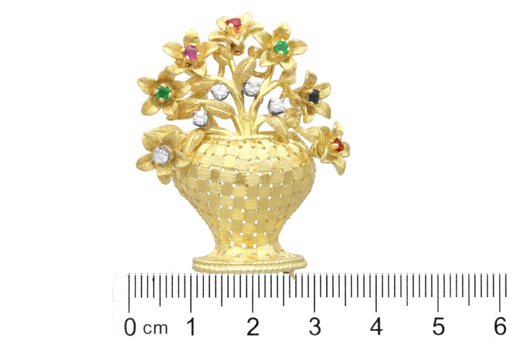 An 18ct yellow gold brooch crafted as a woven basket filled with textured flowers set with multi-coloured gemstones and diamonds. View XI