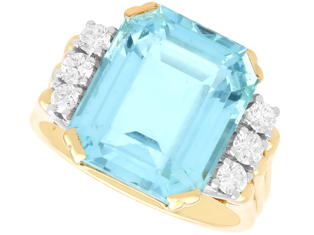 A 14ct yellow gold dress ring featuring a large emerald-cut light blue aquamarine central gemstone flanked by six round diamonds.