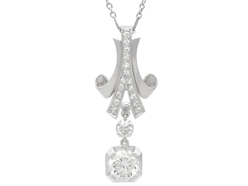 An Art Deco platinum pendant set with brilliant-cut diamonds featuring a geometric ribbon motif suspended above a central diamond drop.