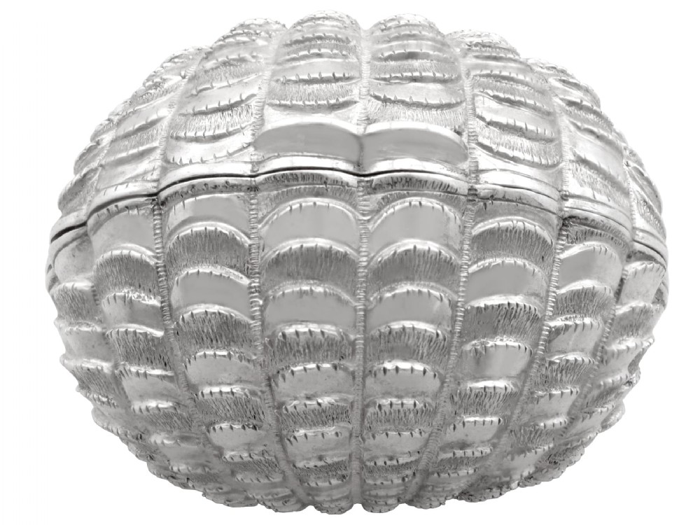 An antique Victorian sterling silver nutmeg grater featuring a textured ribbed shell form with a hinged lid.