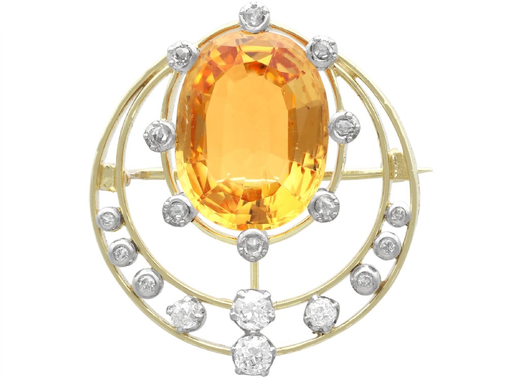 A circular 14ct yellow gold openwork brooch featuring a central oval cut yellow topaz framed by diamond settings.