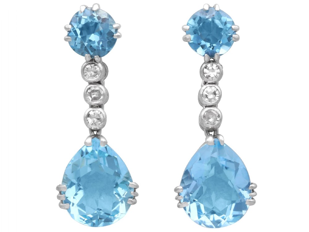 A pair of 14ct white gold drop earrings featuring round and pear-cut light blue aquamarines joined by a vertical line of small round diamonds.