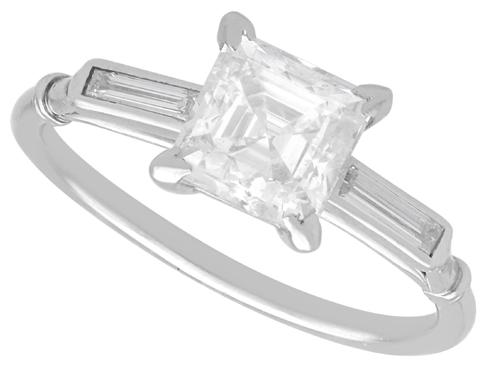 An Art Deco platinum ring featuring a central square step-cut diamond set between two horizontal baguette side stones.