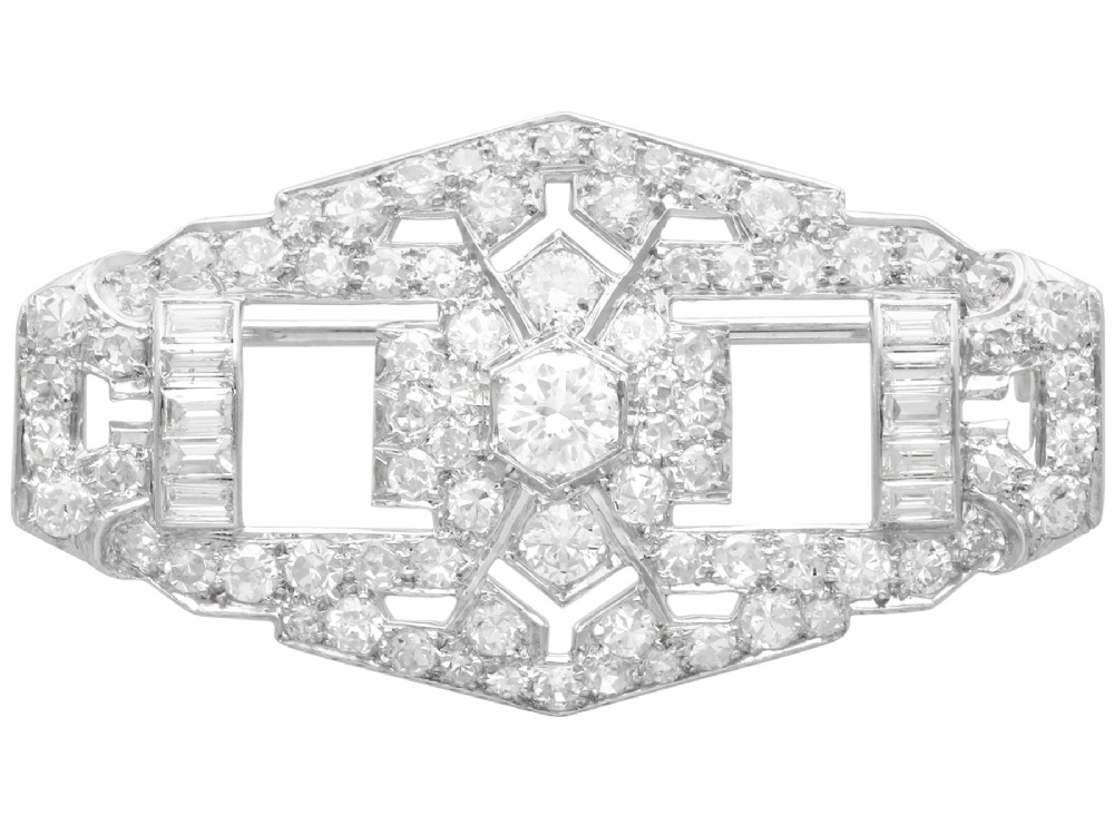 An Art Deco platinum plaque brooch featuring an intricate geometric openwork setting encrusted with round and baguette cut diamonds.