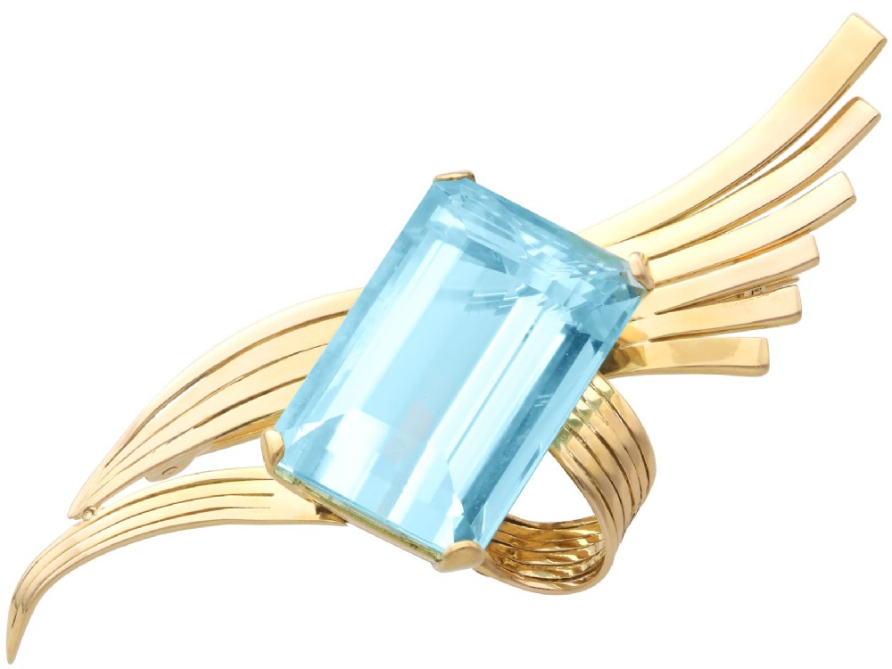 A large emerald-cut blue aquamarine set within a sweeping, ribbed 18ct yellow gold mount.