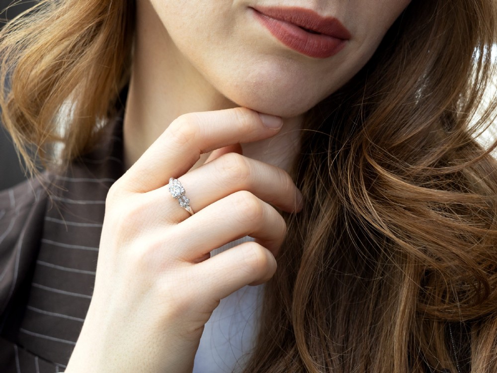 A platinum Art Deco solitaire ring featuring a central round diamond with geometric diamond-set shoulders. View III
