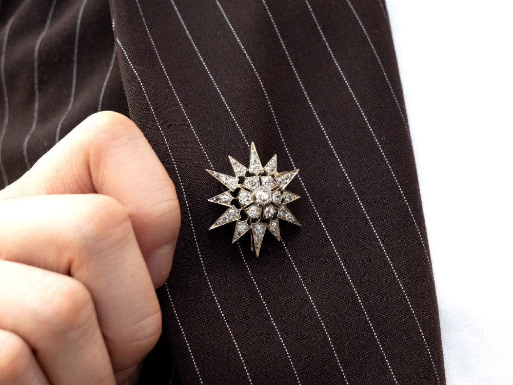 An antique silver and gold starburst brooch set with central and radiating diamonds, suspended from a fine gold chain. View III