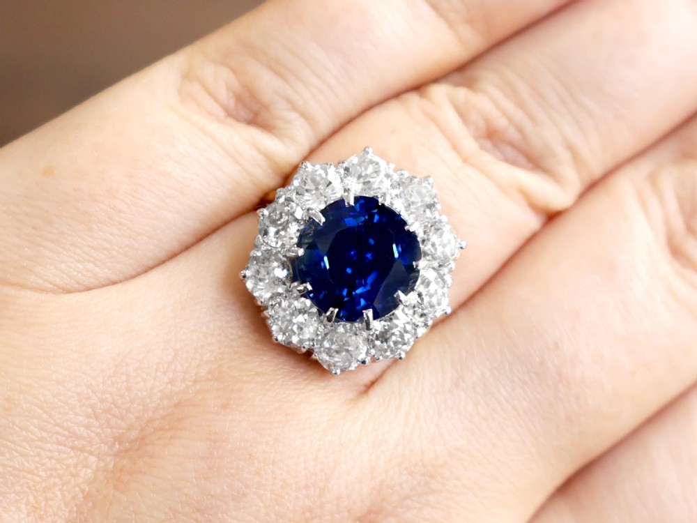 A round deep blue sapphire framed by a halo of ten round brilliant diamonds on an 18ct yellow gold band. View V