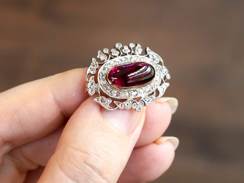 Victorian oval cabochon garnet brooch framed by a halo of diamonds and an ornate leaf openwork border. View III