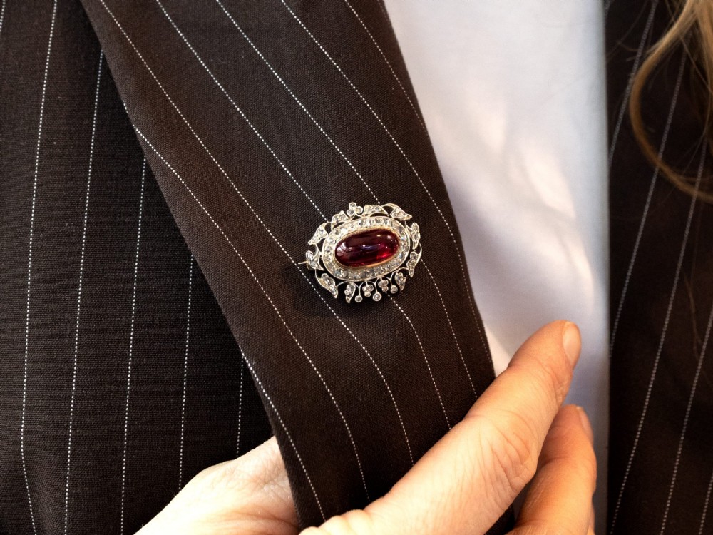 Victorian oval cabochon garnet brooch framed by a halo of diamonds and an ornate leaf openwork border. View IV