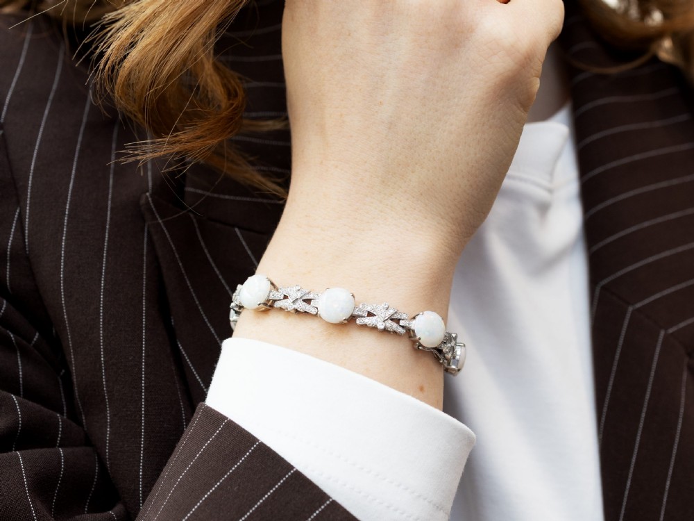 An 18ct white gold bracelet featuring oval cabochon white opals interspersed with geometric diamond-paved links. View IV