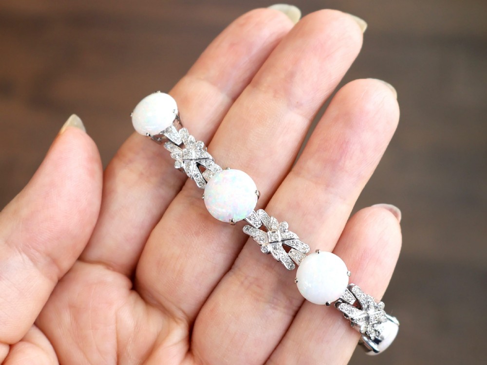 An 18ct white gold bracelet featuring oval cabochon white opals interspersed with geometric diamond-paved links. View V