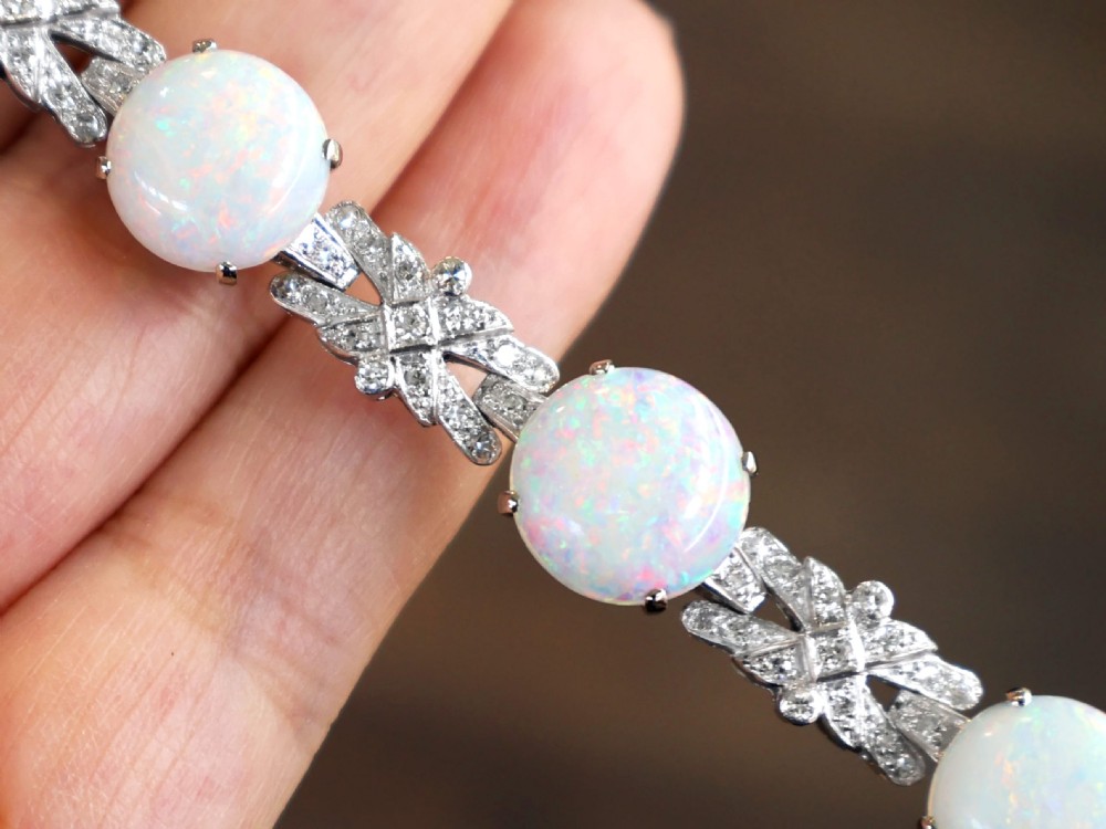 An 18ct white gold bracelet featuring oval cabochon white opals interspersed with geometric diamond-paved links. View VI