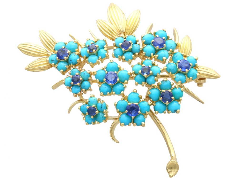 An 18ct yellow gold floral spray brooch featuring cluster settings of round blue sapphires surrounded by cabochon turquoise stones.