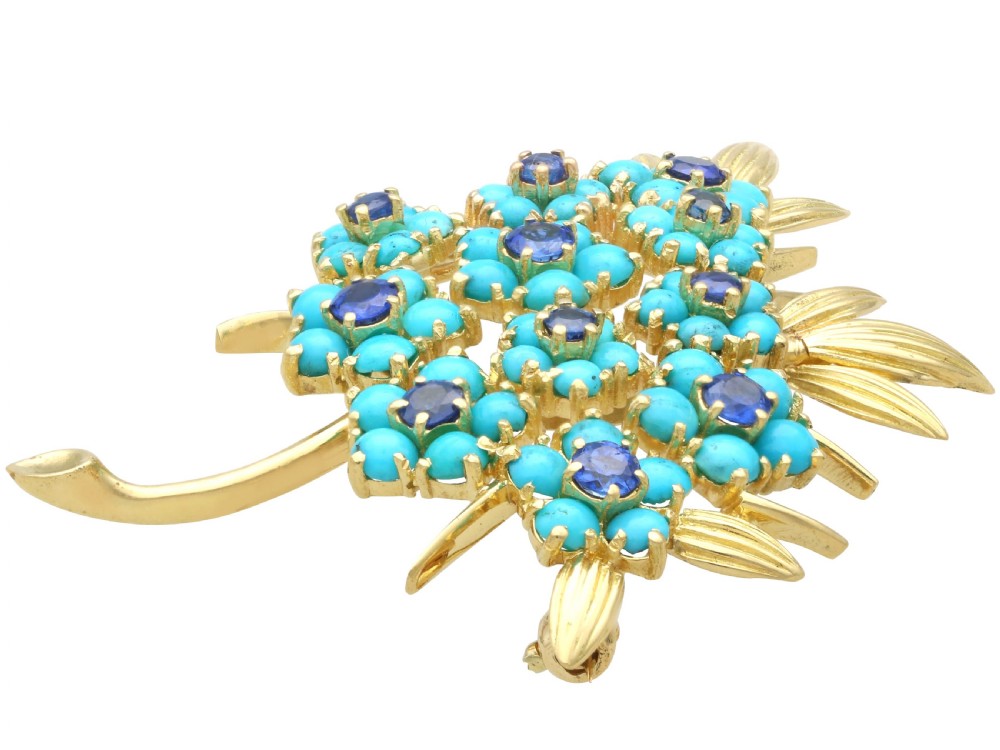 An 18ct yellow gold floral spray brooch featuring cluster settings of round blue sapphires surrounded by cabochon turquoise stones. View III