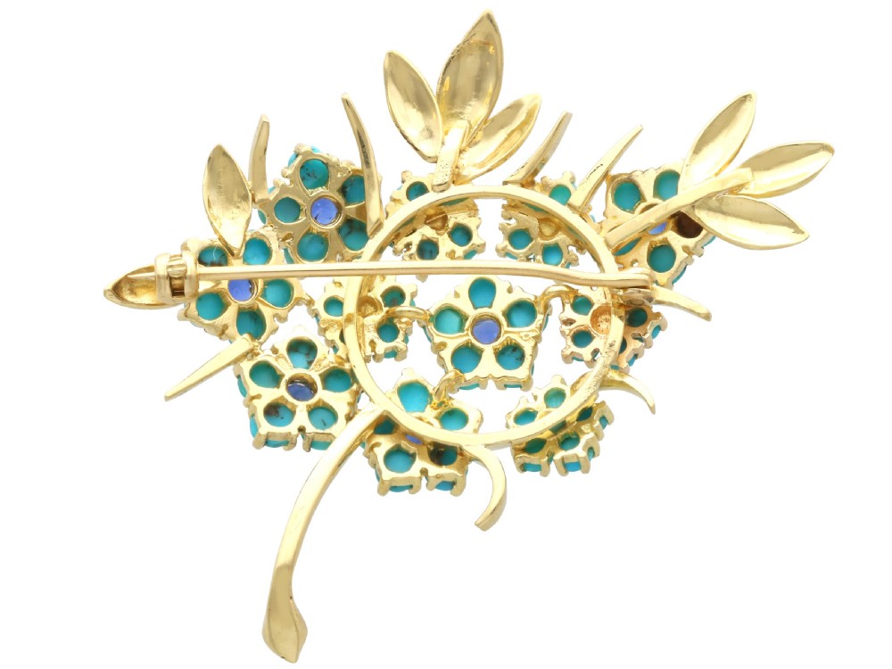 An 18ct yellow gold floral spray brooch featuring cluster settings of round blue sapphires surrounded by cabochon turquoise stones. View IX