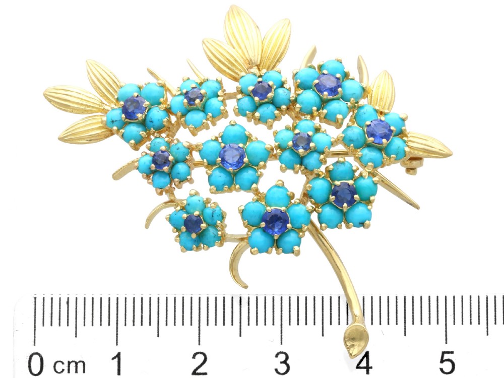 An 18ct yellow gold floral spray brooch featuring cluster settings of round blue sapphires surrounded by cabochon turquoise stones. View XI