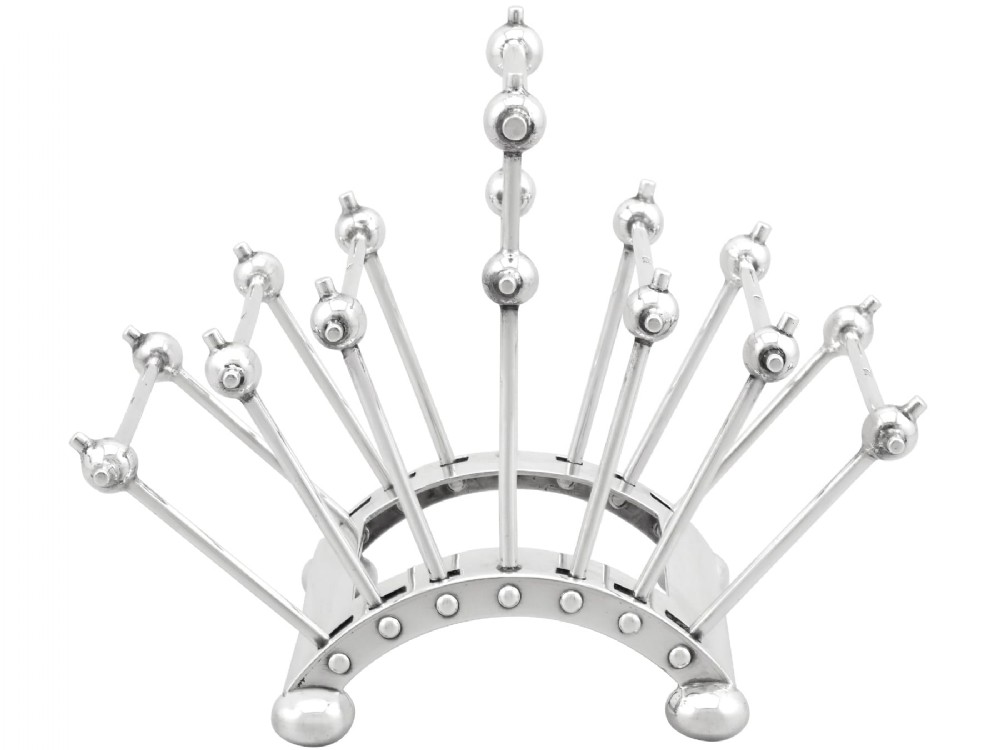 An Edwardian sterling silver toast rack featuring a curved base and fan-shaped radiating dividers topped with spherical details.